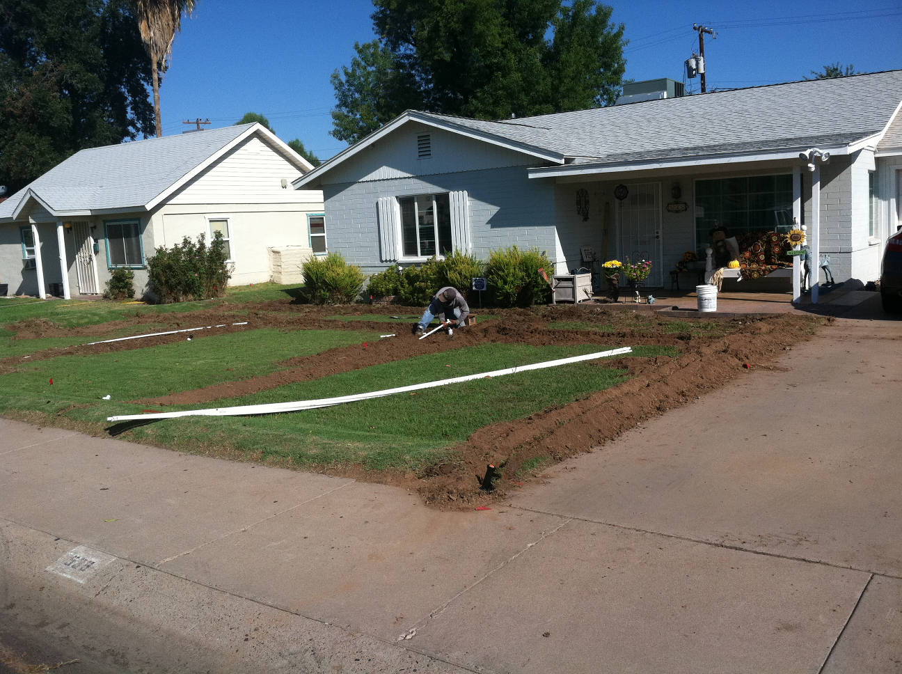 Man setting pipe into trenches in the front yard of a residential home