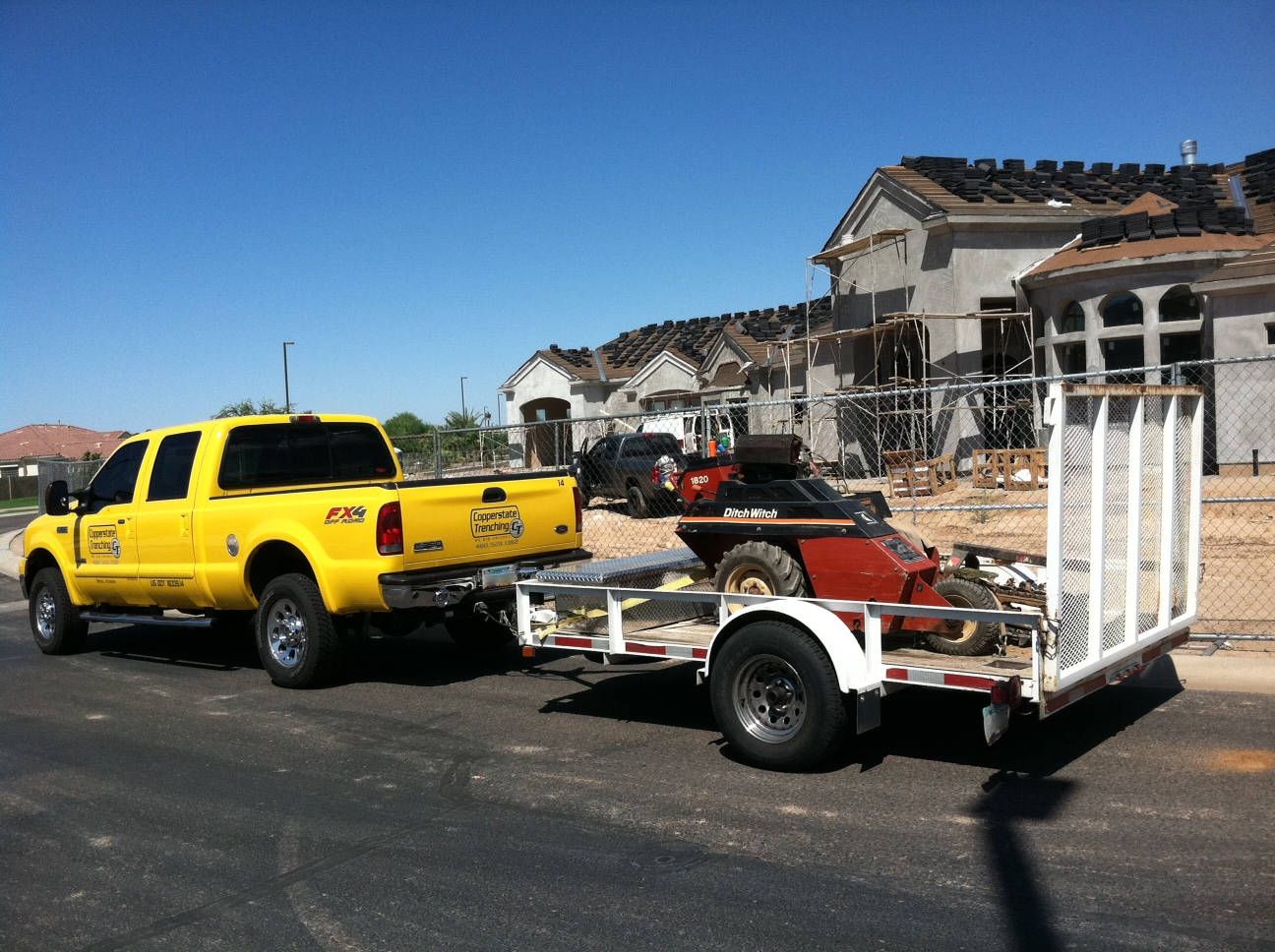 Truck with Copperstate Trenching logos attached to a trailer containing a Ditch Witch trenching machine