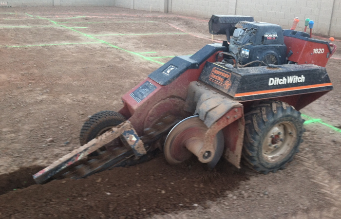 Photo of a Ditch Witch trenching machine digging a trench.